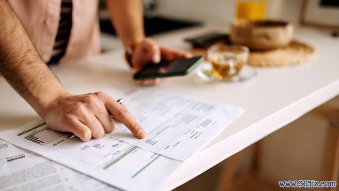 Unrecognisable man using calculator on the phone to calculate expenses